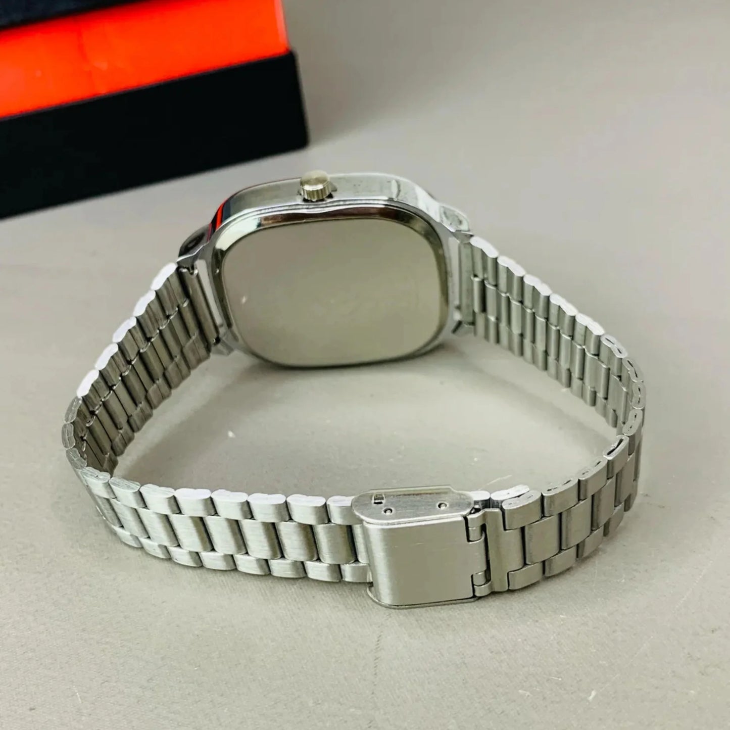 Silver watch with metal band on a light gray surface
