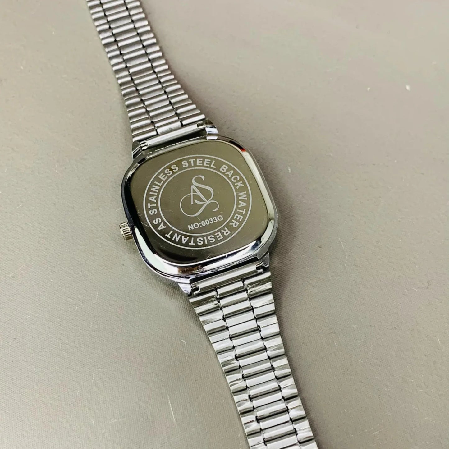 Silver watch with metal band on a light gray background